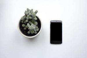 zwarte mobiele telefoon op witte achtergrond, bovenaanzicht van smartphone en interieurdecoraties foto