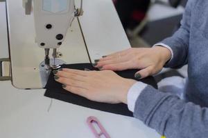 naaister aan het werk aan tafel, kleermaker vrouw werk in studio met kleding foto