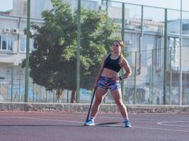 jonge sterke vrouw die in de zomer buiten traint, vrouwelijke professionele atleet doet oefeningen in het park foto