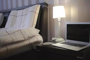 laptop in slaapkamer met bed, lamp en home decor achtergrond. foto