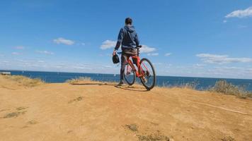 jonge man op de fiets met helmrit op het strand foto