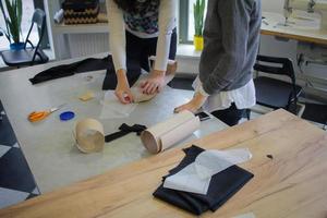 naaister aan het werk aan tafel, kleermaker vrouw werk in studio met kleding foto