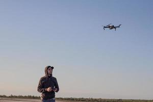foto van zwarte villen quadrocopter dron en piloot siluette in zonsondergang lichte achtergrond, toeristen gebruiken dron helikopter om te fotograferen of te filmen woestijnlandschappen