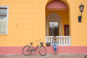 jonge vrouw fietser gebruikt mobiele telefoon, stedelijke achtergrond foto