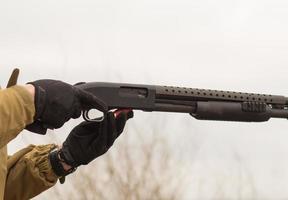 mannelijke training met pompactie shotgun buiten in het veld. foto