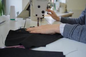 naaister aan het werk aan tafel, kleermaker vrouw werk in studio met kleding foto