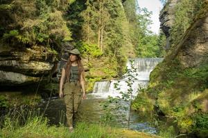 jonge vrouw wandelaar poseren in de buurt van de rivier in bohemien zwitserland nationaal park, vrouwelijke reiziger in de bergen van tsjechië foto