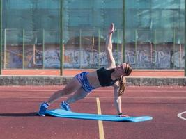 jonge sterke vrouw die in de zomer buiten traint, vrouwelijke professionele atleet doet oefeningen in het park foto