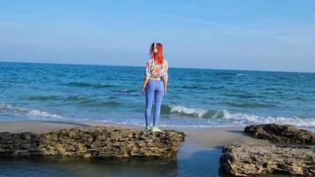 jonge vrouw met kleurrijk haar loopt op het zomerstrand en luistert naar muziek met een koptelefoon foto