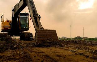 backhoe geparkeerd op de bouwplaats na het graven van grond. close-up emmer bulldozer. graver na het werk. grondverzetmachine op de bouwplaats van een woonwijk. graver met vuilemmer en grond. foto