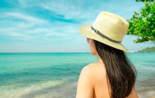 achteraanzicht van sexy jonge Aziatische vrouw dragen roze bikini, strohoed en zonnebril ontspannen en genieten van vakantie op tropisch paradijs strand. meisje in zomervakantie mode. schoonheid sexy model. zomerse sferen. foto