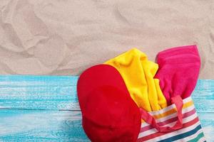 zand kopie ruimte. zand achtergrond bovenaanzicht. strandlakens in een strandtas en een rode muts foto