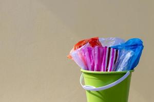 plastic zakken zijn verpakt in een groene container met een gele betonnen wand. foto