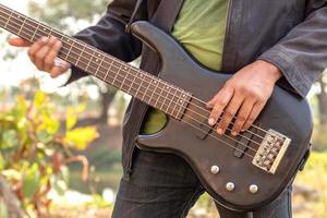 dicht bij de handen van mannen die buiten basgitaar spelen. foto