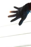 silhouethand die blauwe handschoenen met lichte lamellen draagt. foto