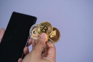 gouden bitcoin munt dogecoin doge, ethereum eth groep opgenomen met cryptocurrency bij de hand vrouw of meisje en mobiele telefoon smartphone geplaatst zetten en geven paarse achtergrond. online winkelconcept. foto