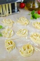 verse zelfgemaakte pastamachine pasta, basilicum, tomaten op een houten foto