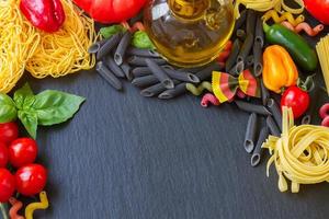 rauwe pasta met ingrediënten op zwarte bord