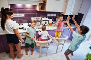 moeder met kinderen die koken in de keuken, gelukkige kindermomenten. geef elkaar een high five. foto