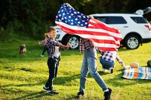 Amerikaanse familie tijd samen doorbrengen. broers spelen met usa-vlaggen tegen grote suv-auto buiten. Amerika vieren. foto