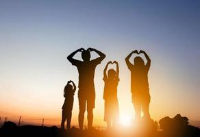 silhouet van vader moeder en twee kinderen die plezier hebben op zonsondergang, gelukkige familie concept. foto