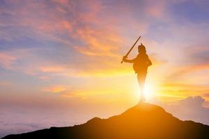 silhouet van zakelijke vrouw ridder zwaard en schild in zonsondergang achtergrond, strijd zakelijke krijger concept, met uitknippad. foto