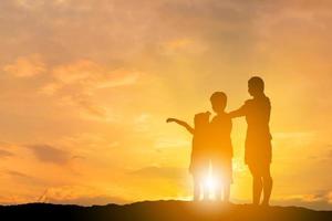 silhouet van broer en zus rende naar moeder bij zonsondergang achtergrond, gelukkig moeder en kind concept, met uitknippad. foto