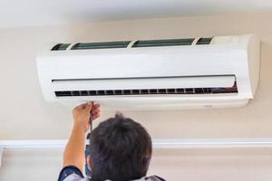 mannelijke technicus die airconditioner binnenshuis repareert, reparateur die vuile compartimenten wast airconditioner, onderhouds- en reparatieconcepten foto