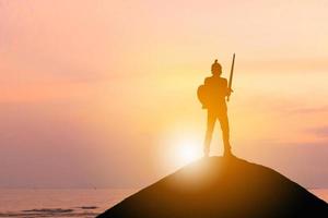 silhouet van zakenman ridder zwaard en schild op zonsondergang achtergrond, strijd zakelijke krijger concept. foto