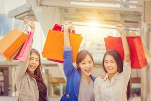gelukkig winkelen drie mooie jonge vrouwelijke vrienden met tassen op straat, groep blanke vrouwen die in de stad kopen. foto
