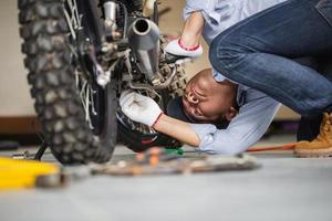 man die motorfiets repareert in reparatiewerkplaats, monteur die motor in werkplaatsgarage repareert, reparatie- en onderhoudsconcepten foto