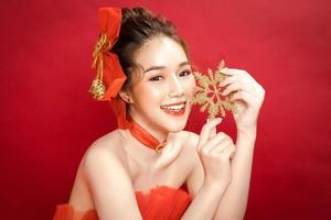 jonge Aziatische mooie vrouw model in een chique stijlvolle luxe rode jurk op een rode achtergrond geïsoleerd. foto