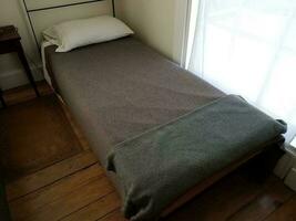 klein smal oud bed met grijze en zwarte dekens foto