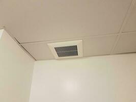 metalen ventilatierooster of register op het plafond met witte muren foto