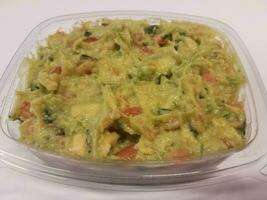 plastic container met avocado of guacamole op wit oppervlak foto