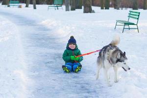 gelukkige jongen speelt met husky hond in winterpark vol sneeuw foto