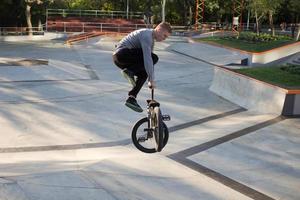 bmx-rijderstraining en trucs doen op straatplein, fietsstuntrijder in cocncrete skatepark foto