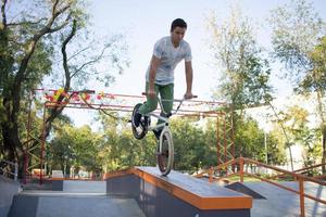 bmx-rijderstraining en trucs doen op straatplein, fietsstuntrijder in cocncrete skatepark foto