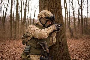 man van particulier militair bedrijf met geweer in het bos foto