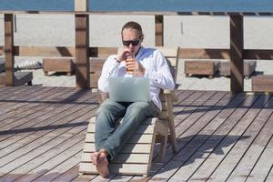 jonge mannen met laptop aan het werk bij het zwembad, freelancer in hotel op vakantie met notebook foto