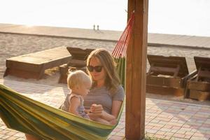 jonge moeder ontspannen met dochter in hangmat op het strand foto