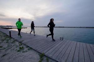 groep jongeren die buiten traint, hardlopersoefeningen, zee- of rivierachtergrond foto