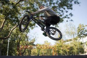 bmx-rijderstraining en trucs doen op straatplein, fietsstuntrijder in cocncrete skatepark foto