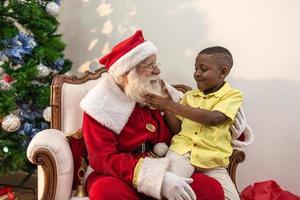 de kerstman levert een geschenkdoos aan een kleine Afrikaanse jongen. kerstavond, levering van geschenken. foto