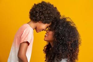 portret van jonge Afro-Amerikaanse moeder met peuter zoon. gele achtergrond. Braziliaanse familie. foto