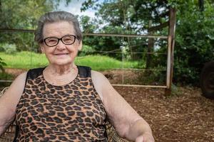 Senior gelukkige oude boer vrouw met bril glimlachen en kijken naar camera foto