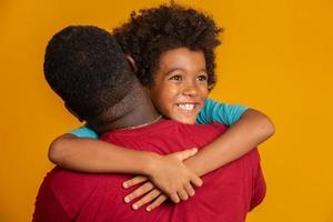 Afrikaanse vader en zoon spelen superheld op het moment van de dag. mensen die plezier hebben gele achtergrond. concept van vriendelijke familie. foto