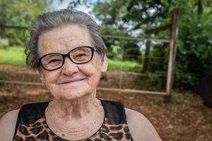 Senior gelukkige oude boer vrouw met bril glimlachen en kijken naar camera foto