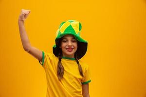 voetbalsupporter, braziliaans team. wereldbeker. mooi klein meisje juichen voor haar team op gele achtergrond foto