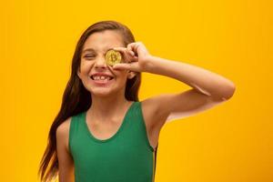 kind met cryptocurrency in metaal. gouden munt. gouden. op gele achtergrond. foto